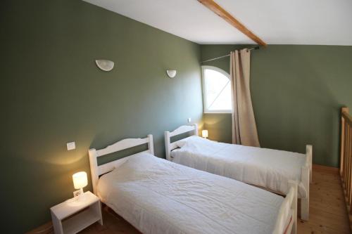 two beds in a green room with a window at La vauloube in Châteauponsac