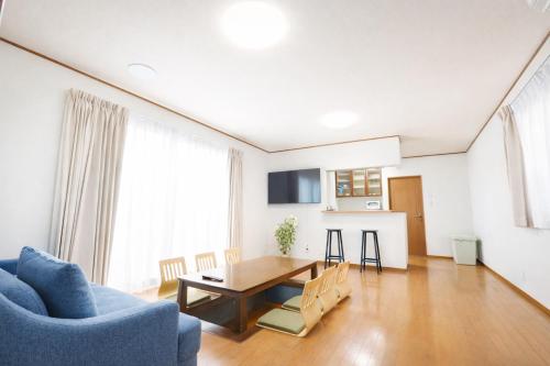 a living room with a table and a blue couch at NEW OPEN 庭音日和 一棟貸し 八幡堀徒歩9分 壺湯2つ 近江牛名店至近 子連れ歓迎 水回り2箇所 p2台 in Omihachiman