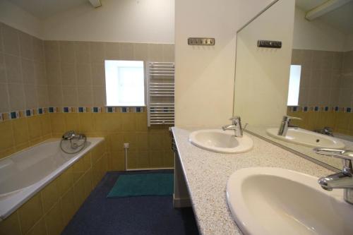 a bathroom with two sinks and a tub and a mirror at Le borland in Nantiat