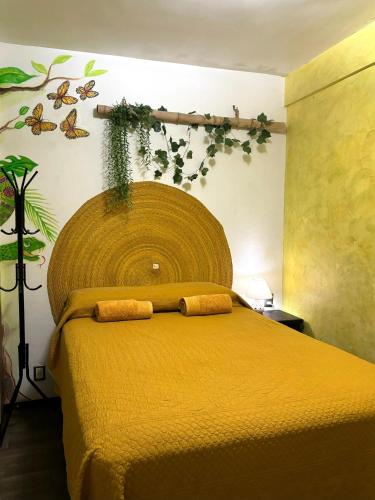 a bedroom with a yellow bed with plants on the wall at Casa los Arcos Oaxaca in Oaxaca City