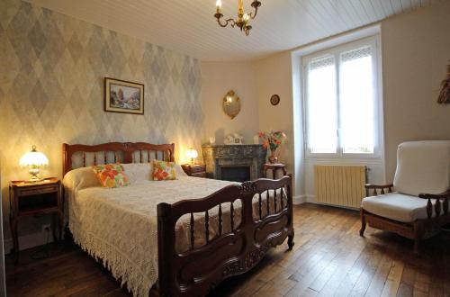 a bedroom with a bed and a chair and a fireplace at Négrignas in Augne