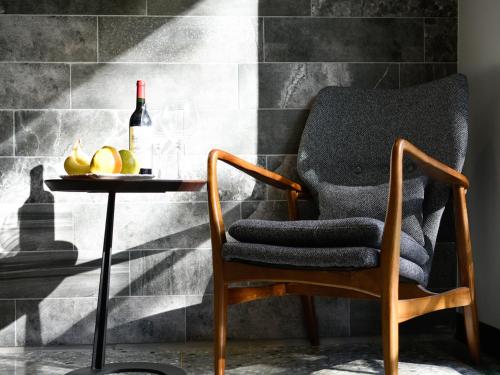 a chair and a table with a bottle of wine and fruit at 3 Door Hotel in Tainan