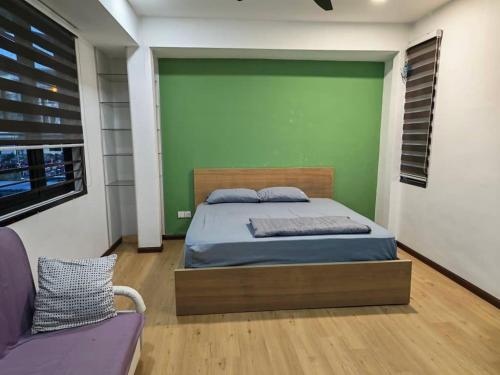 a bedroom with a bed and a green wall at Permas Jaya Corner Homestay -Event -Party -TablePool -Karaoke -BBQ in Johor Bahru