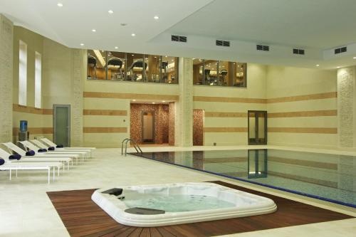 a swimming pool with a hot tub in the middle of a building at Orion Hotel Bishkek in Bishkek