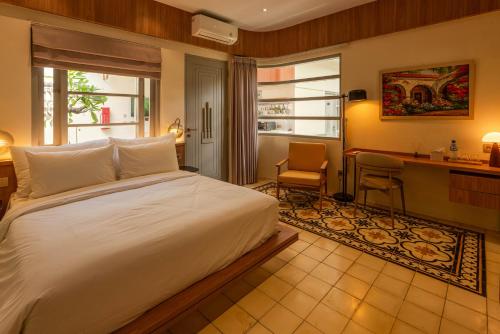 a bedroom with a white bed and a desk and a chair at Villa Ceria Dukuh in Timuran
