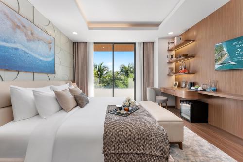 a bedroom with a large white bed and a desk at Costamigo Phan Thiet, BW Premier Collection in Phan Thiet