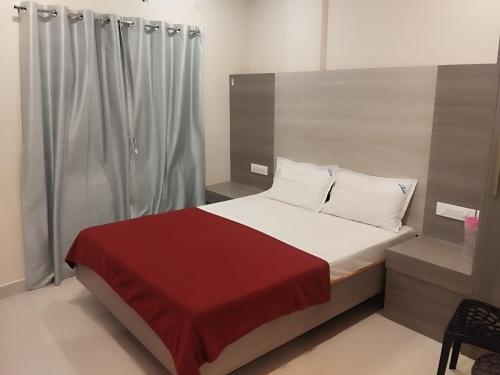 a bedroom with a bed with a red blanket at Hotel Alankar in Kanyakumari