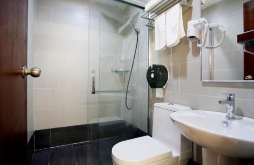 a bathroom with a toilet and a sink and a shower at Kingsley Hotel in Miri