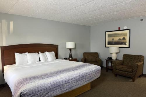 a hotel room with a bed and two chairs at AmericInn by Wyndham Sioux Falls in Sioux Falls