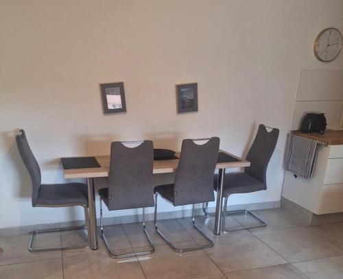 a dining room table with chairs and a clock on the wall at Deck 3 in Cuxhaven