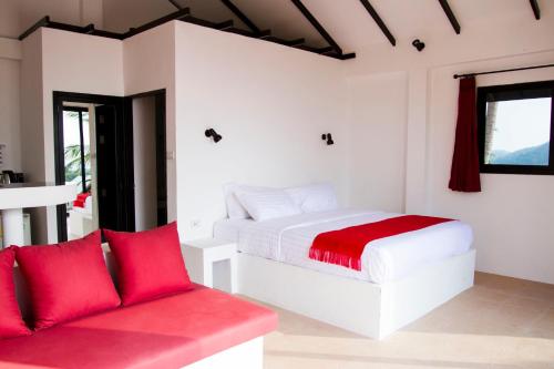 a bedroom with a white bed and a red couch at Karo Villas in Koh Tao