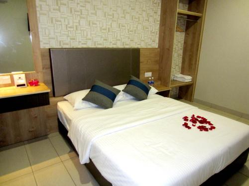 a bedroom with a large white bed with red flowers on it at RG Grand Hotel in Parit Raja