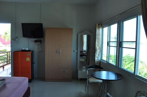 Cette chambre dispose d'une table, d'un réfrigérateur et d'une fenêtre. dans l'établissement The Rim Riverside Guest House, à Nong Khai