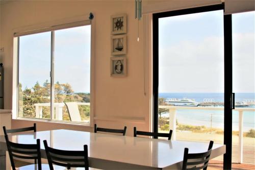 a dining room with a table and chairs and a view of the ocean at Penneshaw Beach House in Penneshaw