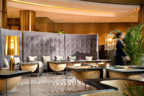 a restaurant with tables and chairs in a lobby at Sofitel Zhengzhou International in Zhengzhou