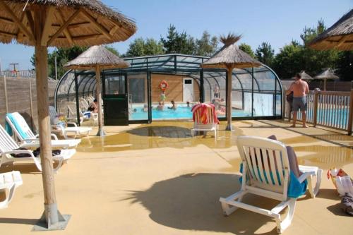 a pool with chairs and umbrellas on a patio at Camping 3 étoiles - Piscine - à 2 minutes des plages in Penvénan