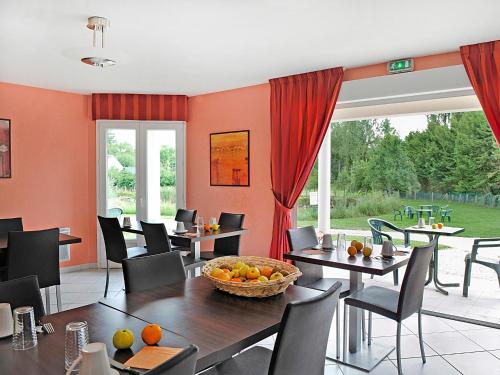 een eetkamer met tafels en stoelen en een groot raam bij L'Orée des Châteaux in Bracieux