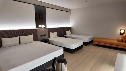 a hotel room with two beds and a couch at Urban Inn, Alor Setar in Alor Setar