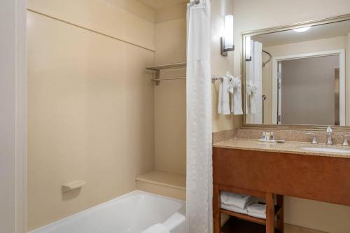 a bathroom with a tub and a sink and a mirror at Comfort Suites Barstow near I-15 in Barstow