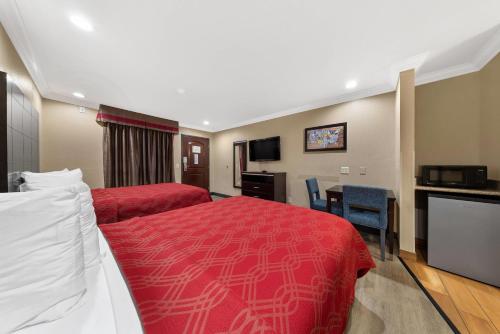 a hotel room with a red bed and a desk at Econo Lodge Inn & Suites Escondido Downtown in Escondido