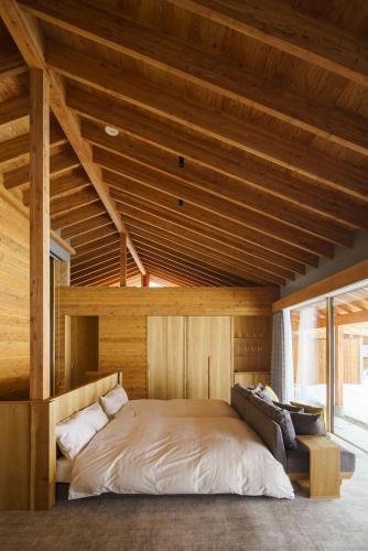 a large bed in a room with a wooden ceiling at ヴィラブラマーレ in Kitahiroshima