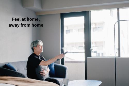 a man sitting in a chair holding a cell phone at Shibuya Apartment Room Dogenzaka in Tokyo