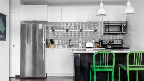 a kitchen with green chairs and a stainless steel refrigerator at The Sobro Guest House by AvantStay in Nashville