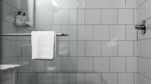 a white tiled bathroom with a towel hanging on a shower at The Sobro Guest House by AvantStay in Nashville