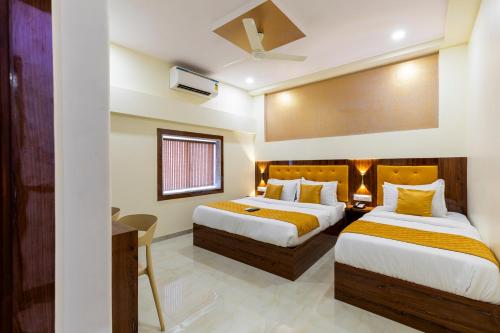 a hotel room with two beds and a desk at Imperial Hotel Near Haji Ali in Mumbai