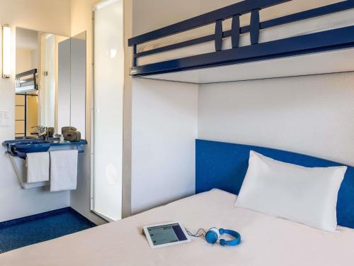 a bedroom with a bed with a laptop and headphones on it at ibis Budget Colmar Centre Gare in Colmar