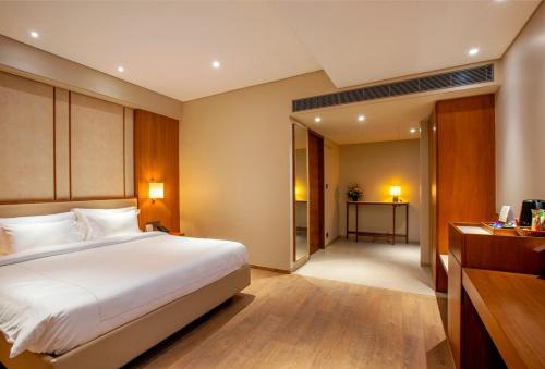 a bedroom with a large white bed and a desk at Purple Elephant Luxury Business Hotel in Cochin