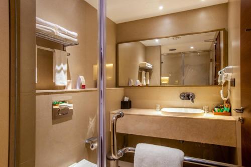 a bathroom with a sink and a mirror at Purple Elephant Luxury Business Hotel in Cochin