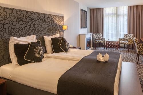 a hotel room with a large bed and a living room at Amsterdam Hotel Uithoorn in Uithoorn