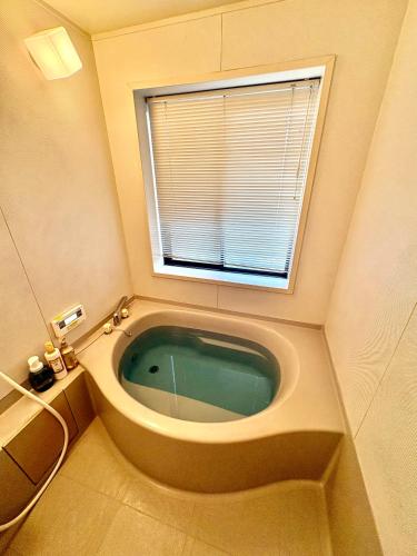 a bath tub in a bathroom with a window at GuestHouse MIYAZAKI for backpakers non smoker喫煙者不可 宮崎駅1Km in Miyazaki
