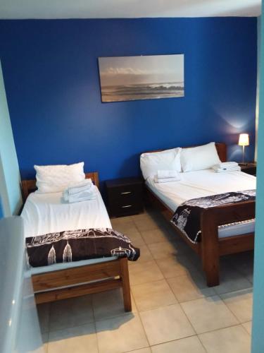 two beds in a room with a blue wall at Ellenas- studios Nikiana Lefkada in Nikiana