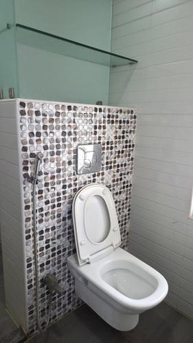 a bathroom with a toilet and a tiled wall at Hotel SK Riverfront in Vijayawāda
