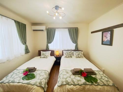 two beds in a small room with a window at 外人住宅ーアメリカンビレッジ車20分 in Urazoe