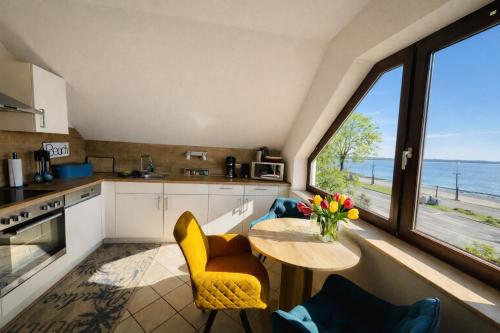 a kitchen with a table and chairs with a view of the ocean at Ferienhaus ,,Pier 7" am See - 2 Wohnungen mit Garten für bis zu 11 Personen, einzeln oder zusammen buchbar in Große Mühle