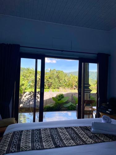 a bedroom with a bed and a large glass window at Adisamasta Guesthouse in Sidemen