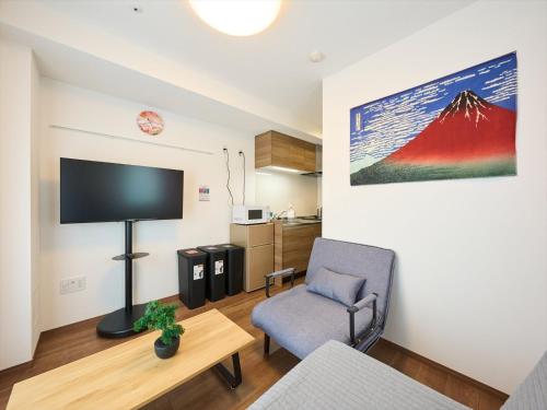 a living room with a chair and a flat screen tv at K-Stay TOKYO HANEDA in Tokyo