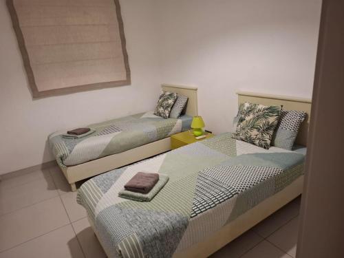 a bedroom with two beds and a yellow lamp on a table at Modern 3BR Apartment in Swieqi in Is-Swieqi