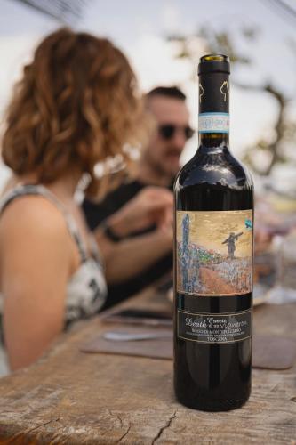 a bottle of wine sitting on a table with a woman at Wild Agriturismo Podere della Bruciata in Chiusi