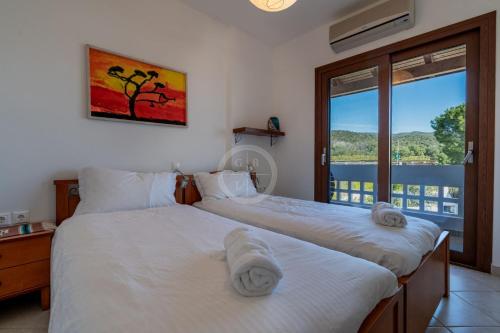 two beds in a room with a window at Villa Rania - Porto Hydra in Ermioni