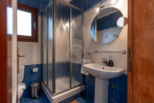 a blue tiled bathroom with a sink and a shower at Villa Rania - Porto Hydra in Ermioni