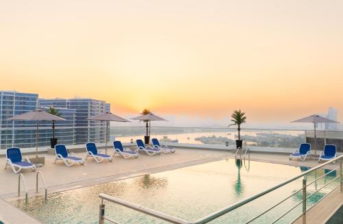 a pool on the roof of a building with chairs and umbrellas at Reya Creek Hotel in Dubai