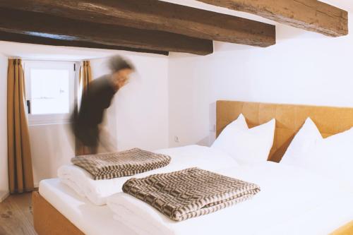a man is standing next to a bed with two pillows at Apartment TrentaTre in Chiusa