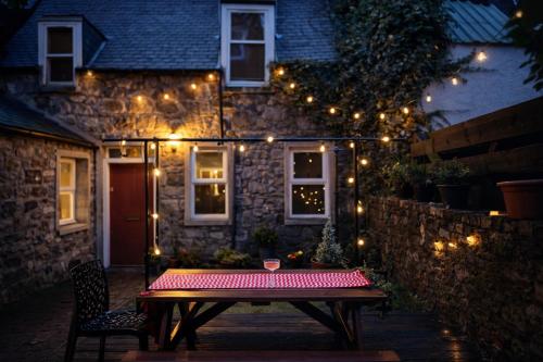 a wooden table in front of a house with lights at Secret City Cottage - Peaceful - Private Garden in Aberdeen