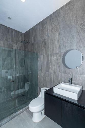a bathroom with a toilet and a sink and a shower at Arch View Luxury Condo with Heated Rooftop Pool and Jacuzzi in Cabo San Lucas