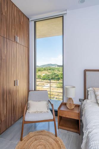a bedroom with a bed and a chair and a window at Arch View Luxury Condo with Heated Rooftop Pool and Jacuzzi in Cabo San Lucas