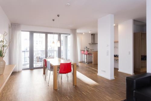 a dining room and kitchen with a table and red chairs at Grimm's Berlin Mitte in Berlin